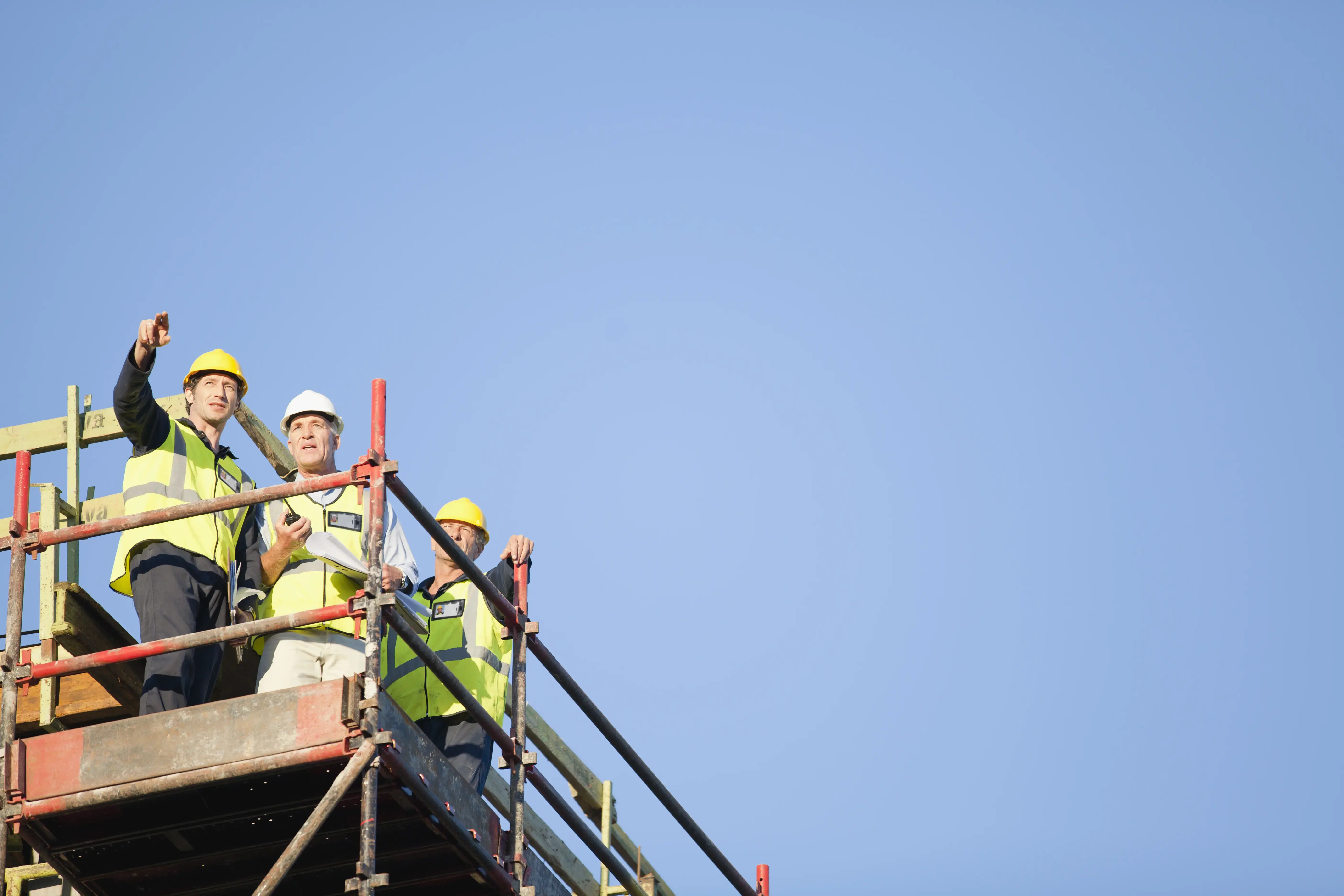 Workers standing on scaffolding on site